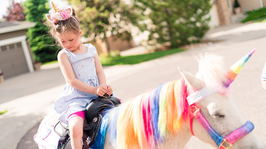 Photo of girl riding a unicorn at a birthday party