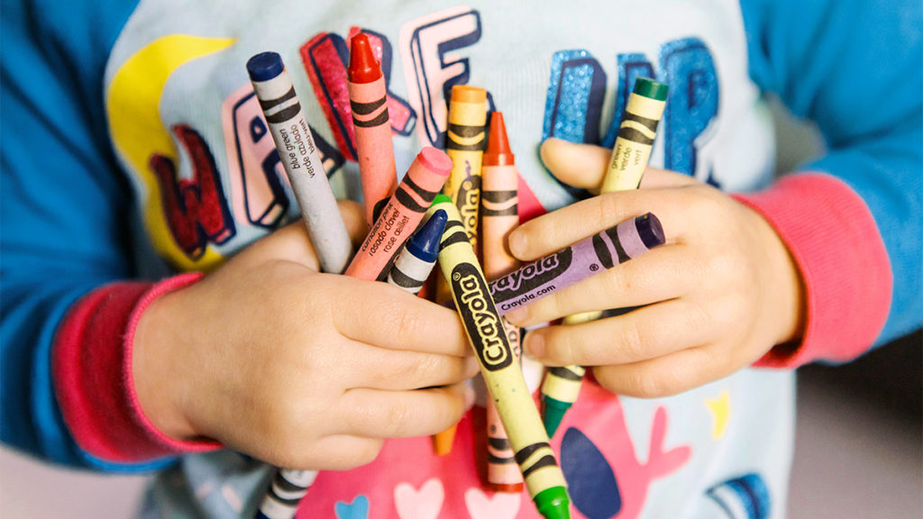 Photo of a kid holding crayons