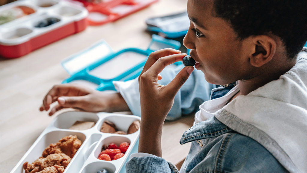 Photo of kid eating lunch at school and finding a lunchbox surprise