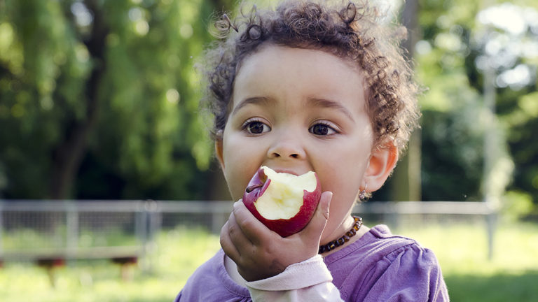 Photo of a kid eating an apple