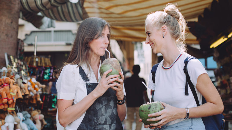 Photo of two women enjoying coconuts