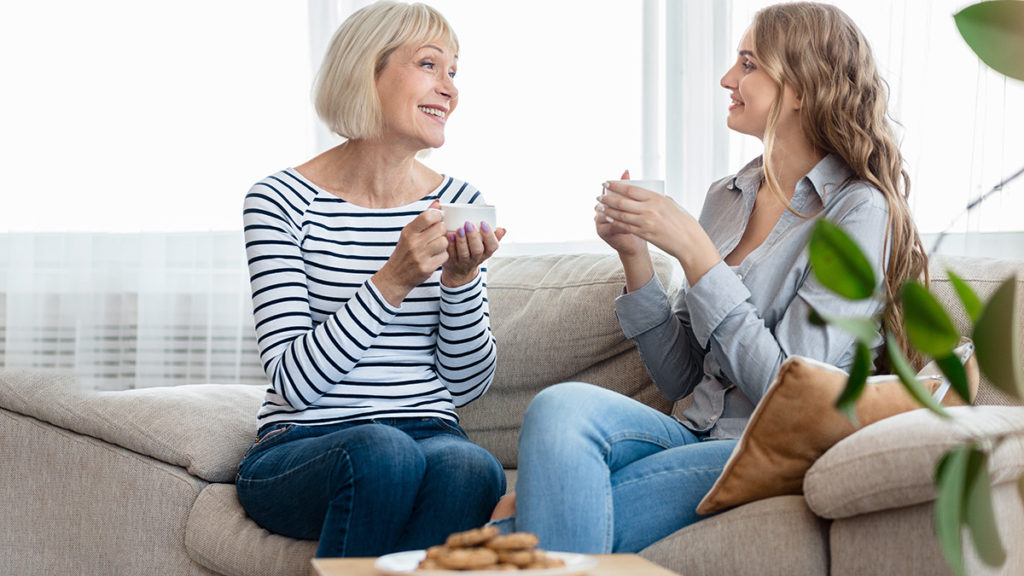 Photo of two women drinking coffee,  eating cookies, and offering words of encouragement to each other.
