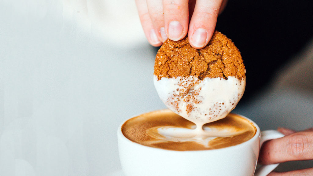 Photo of a person dunking a cookie in a cup of coffee