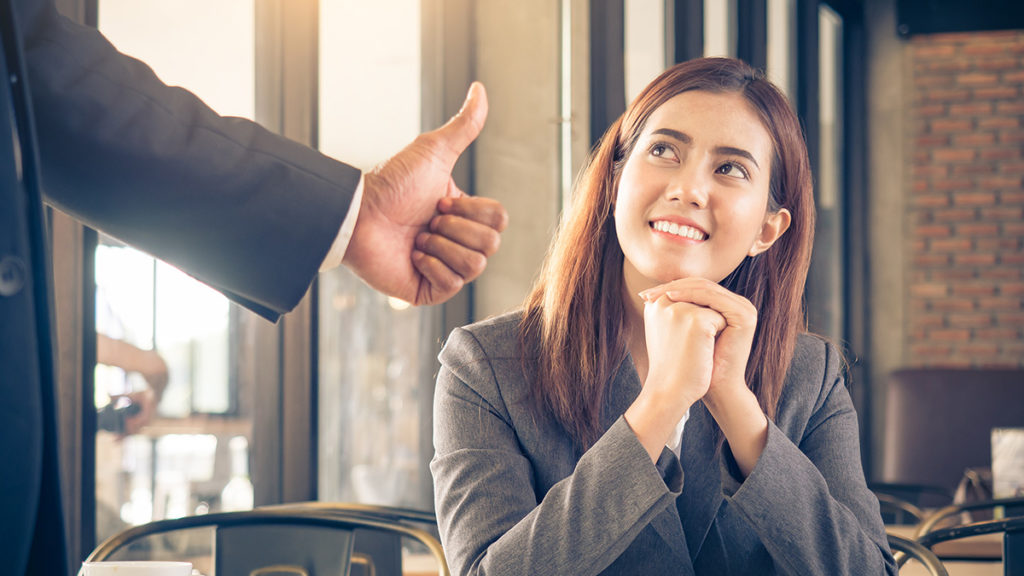 Photo of boss showing an employee appreciation by giving her a thumbs-up