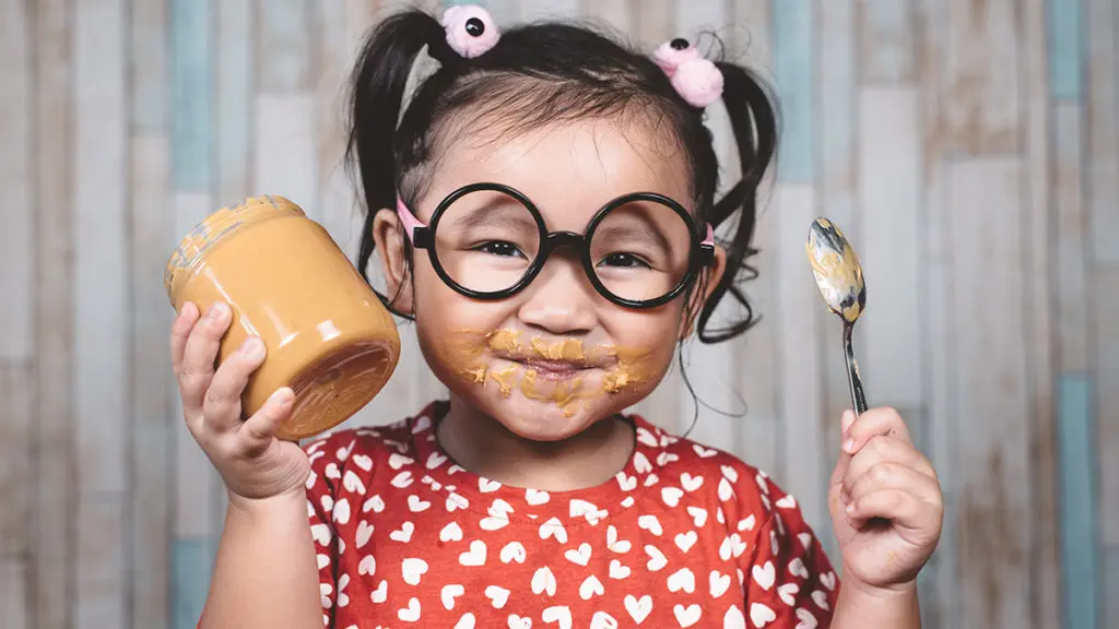 Photo of a girl eating peanut butter