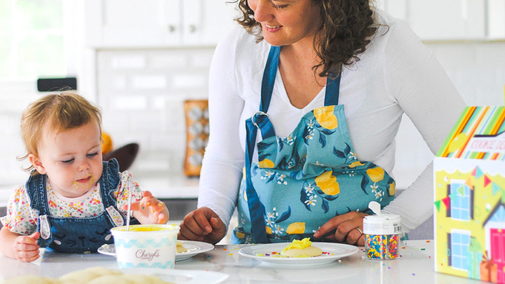 Photo of mother decorating cookies with young daughter
