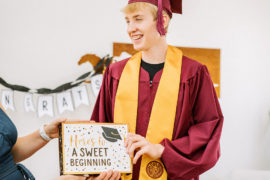 Photo of young man receiving a graduation gift from mother