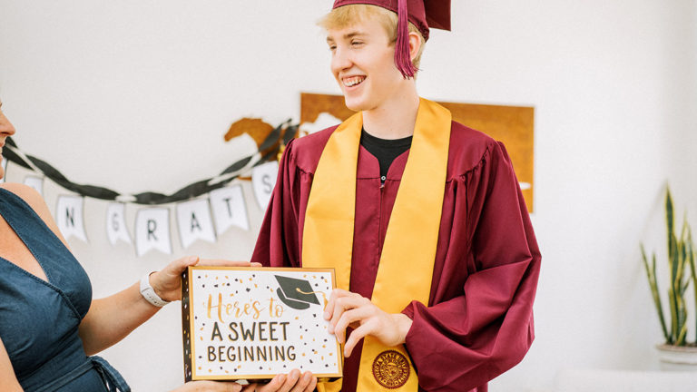 Photo of young man receiving a graduation gift from mother