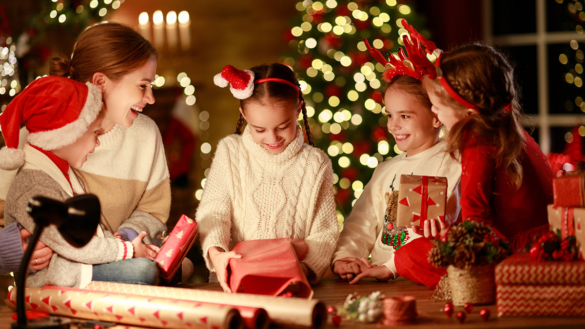 Photo of mom and daughters wrapping presents to elf someone