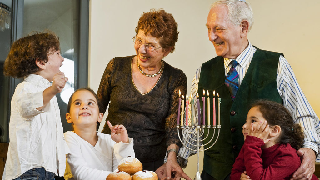 Hanukkah traditions with a family lighting the menorah at the table.