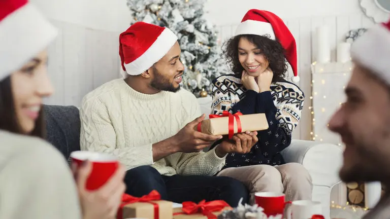 Photo of man surprising woman with Christmas gift