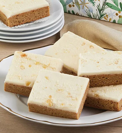 Buttercream frosted gingerbread bars on a plate.