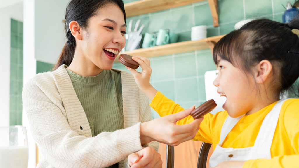 holiday food gifts: mother and daughter feeding each other cookies