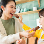 holiday food gifts: mother and daughter feeding each other cookies