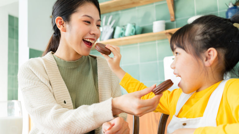 holiday food gifts: mother and daughter feeding each other cookies