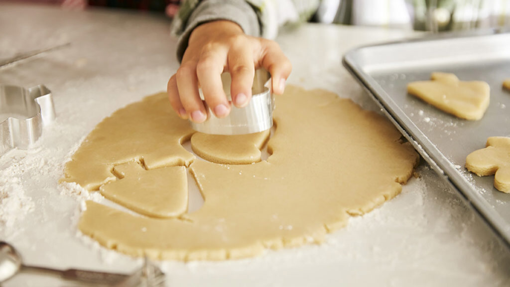 History of Christmas cookies with a small child cutting cookies out of rolled cookie dough.