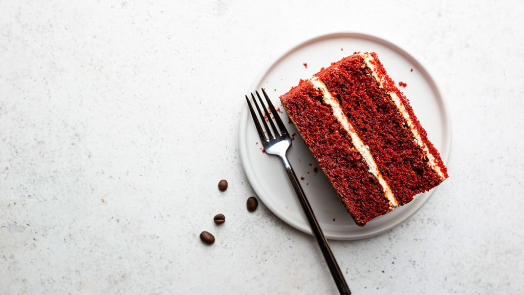 History of red velvet cake with a slice of red velvet cake on a plate.