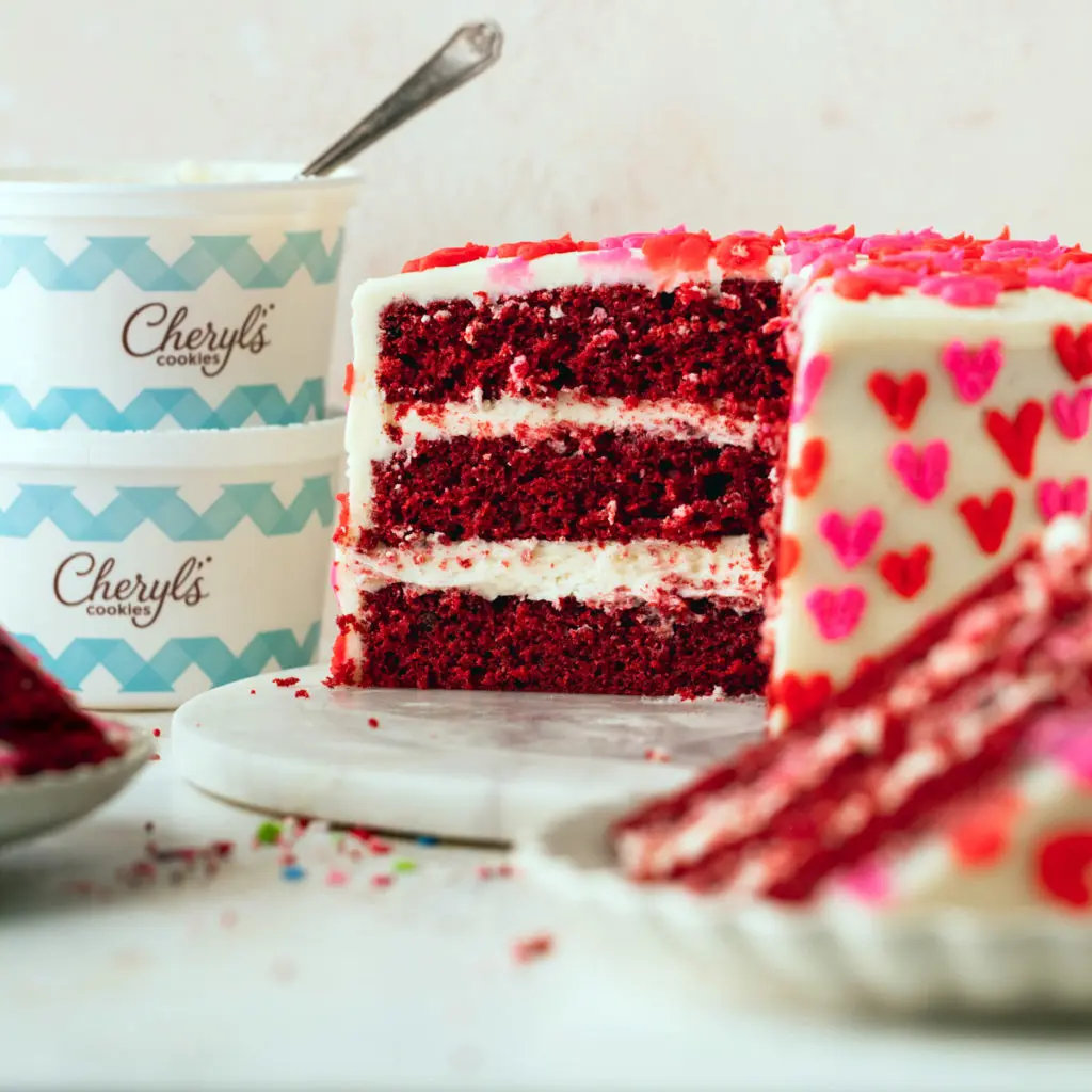 Red velvet cake with a slice cut out on a cake platter.