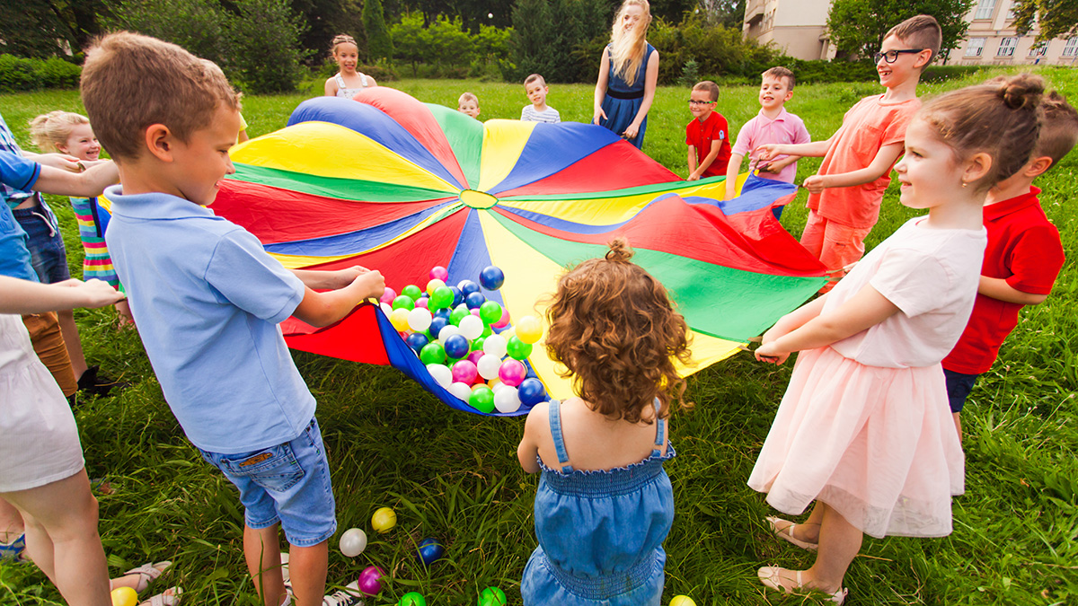 spring birthday party ideas: kids playing with a parachute