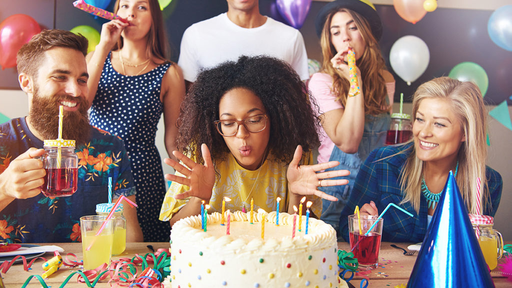 a photo of birthday traditions: woman blowing out candles