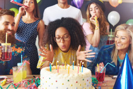 a photo of birthday traditions: woman blowing out candles