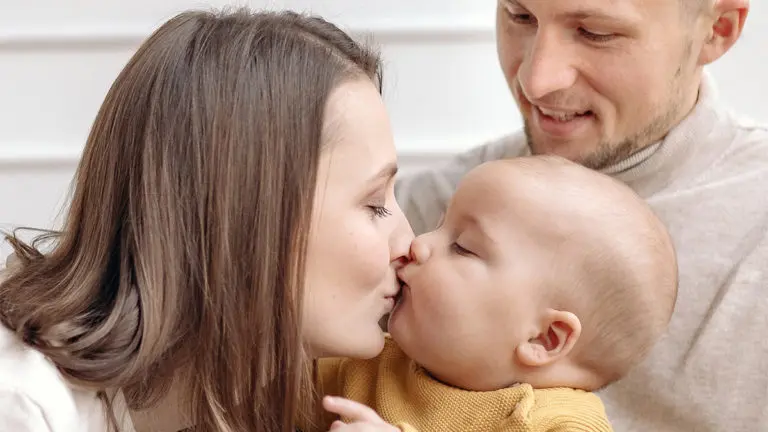 A photo of advice for new parents: new mom kissing baby