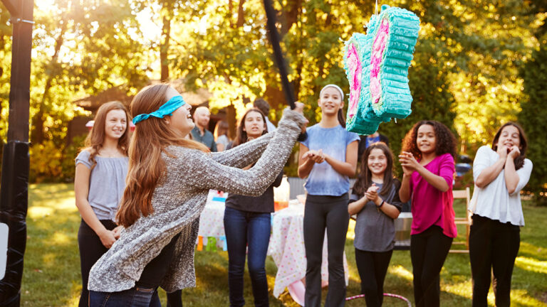 Friends watch teenage girl hitting a pi–ata on her birthday