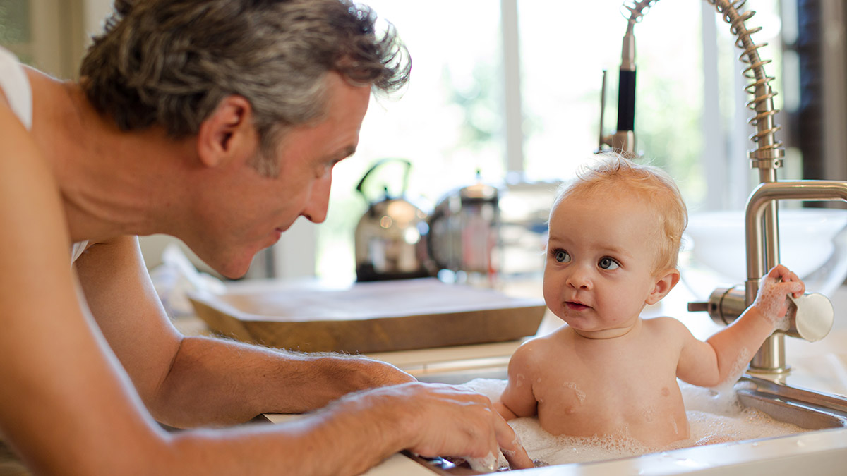 a photo of advice for new parents: dad bathing baby