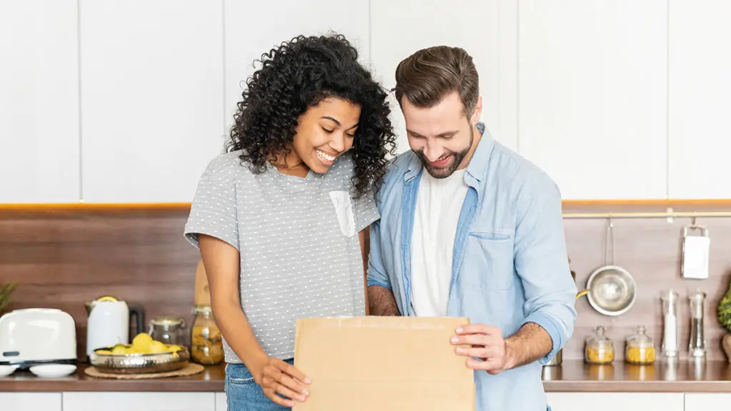 A photo of gifts for new homeowners: couple opening gift in kitchen