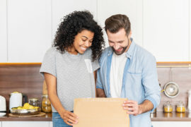 A photo of gifts for new homeowners: couple opening gift in kitchen