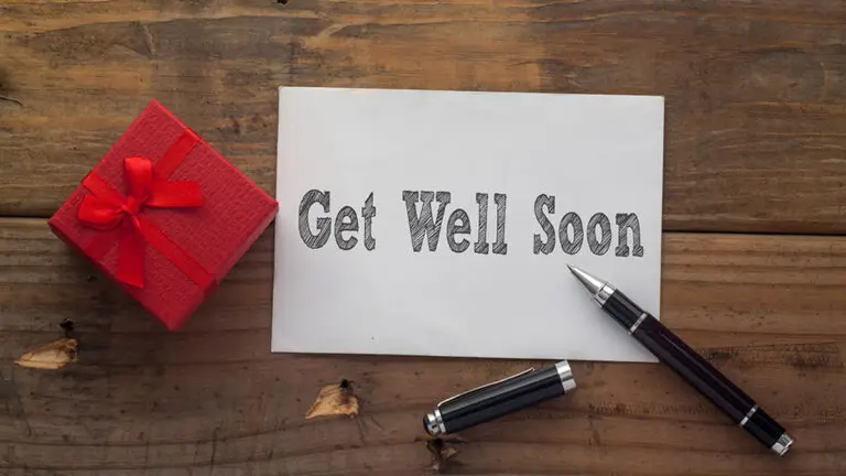 Get Well Soon written on paper with pen,red gift box and wooden background desk.