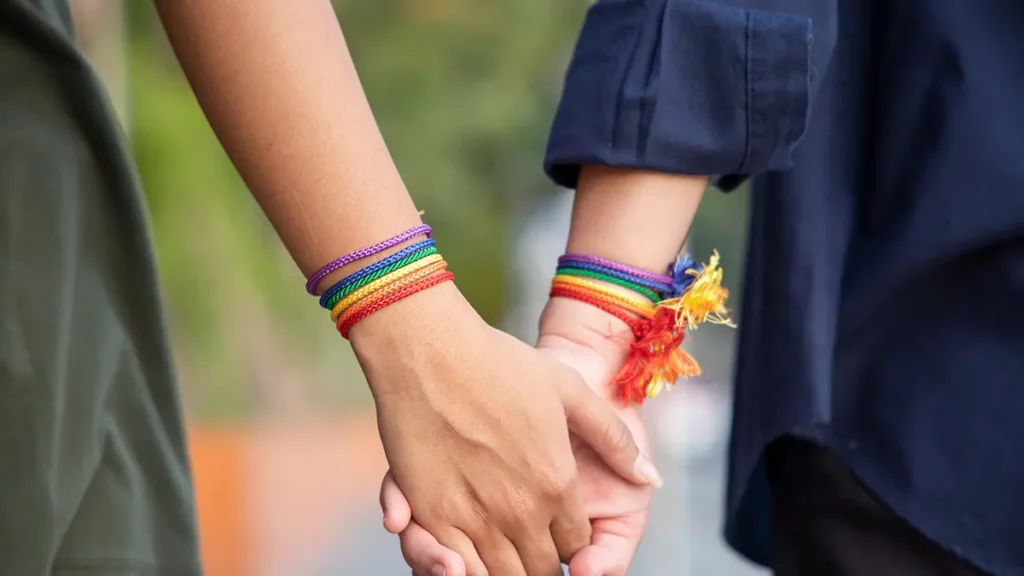 a photo of two women wearing pride bracelets holding hands