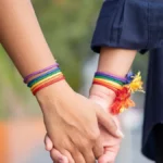 a photo of two women wearing pride bracelets holding hands