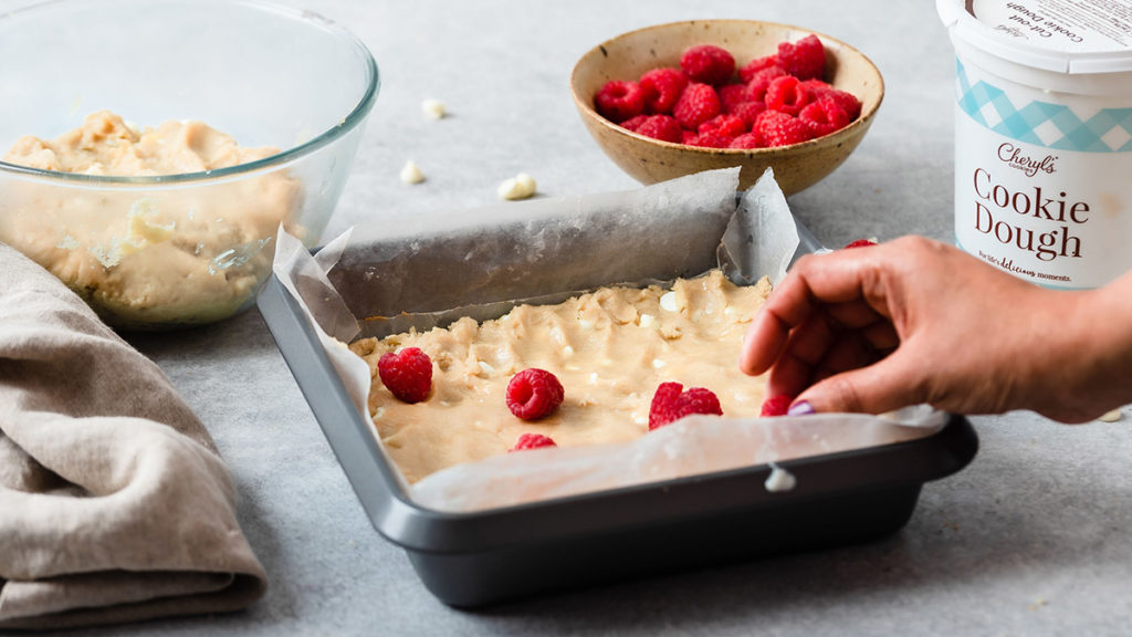 a photo of raspberry white chocolate with dough in the pan and raspberries on top