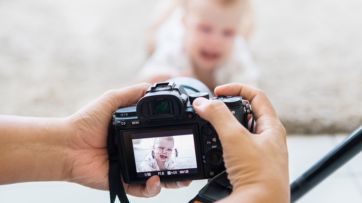 a photo of new parents with dad taking photo of baby