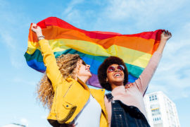 a photo of pride month gifts with two women holding a pride flag