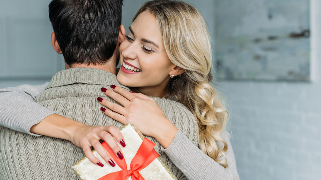 a photo of psychology of gifting with a woman hugging a man after receiving a gift