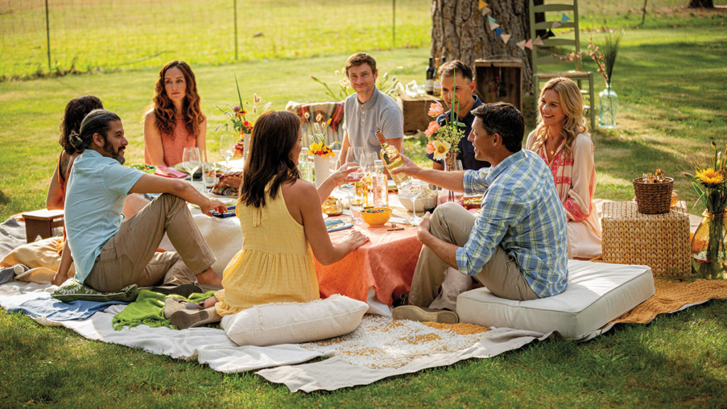 A photo of a picnic with a group of people sitting around a table on the ground outside