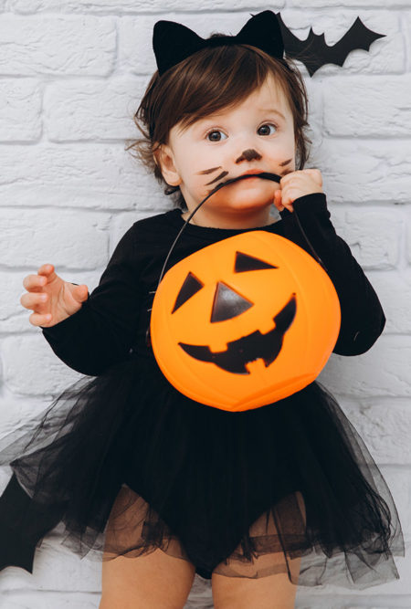 history of halloween toddler girl wearing black cat costume