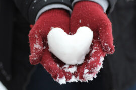 quotes about winter hands wearing red gloves holding a heart-shaped snowball.